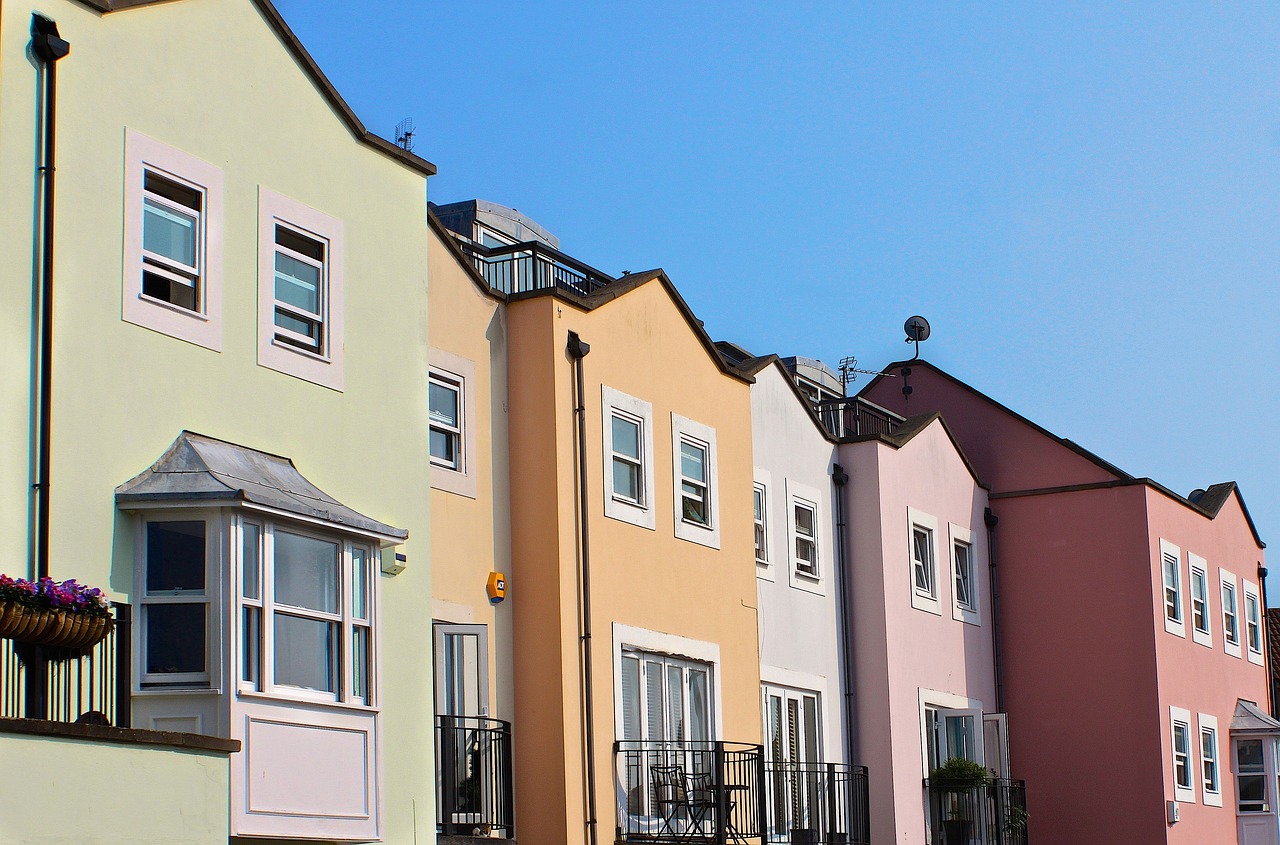 A row of colorful houses with windows and balconies against a blue sky